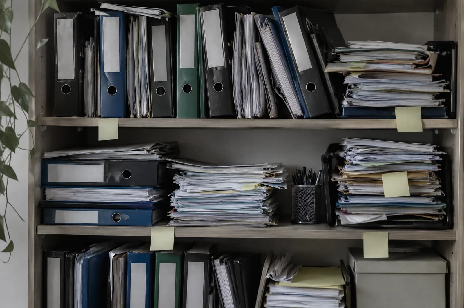 Une étagère d'archives encombrée de classeurs et de piles de papier